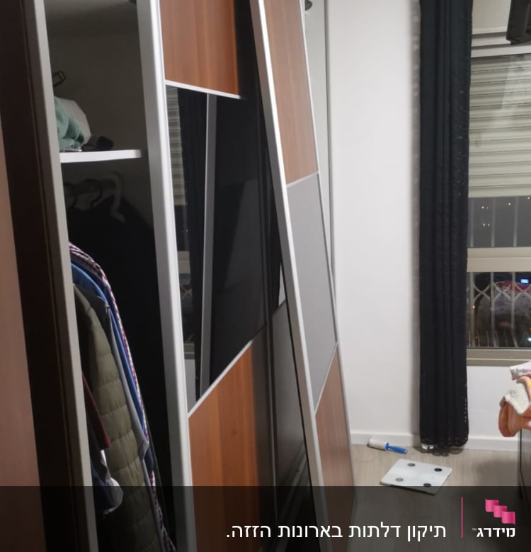 דלת ארון עץ מונחת על הרצפה ליד ארון פתוח